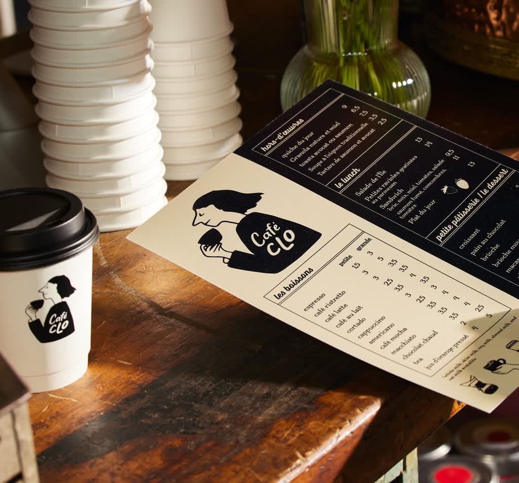 A menu and paper cup with matching café branding.