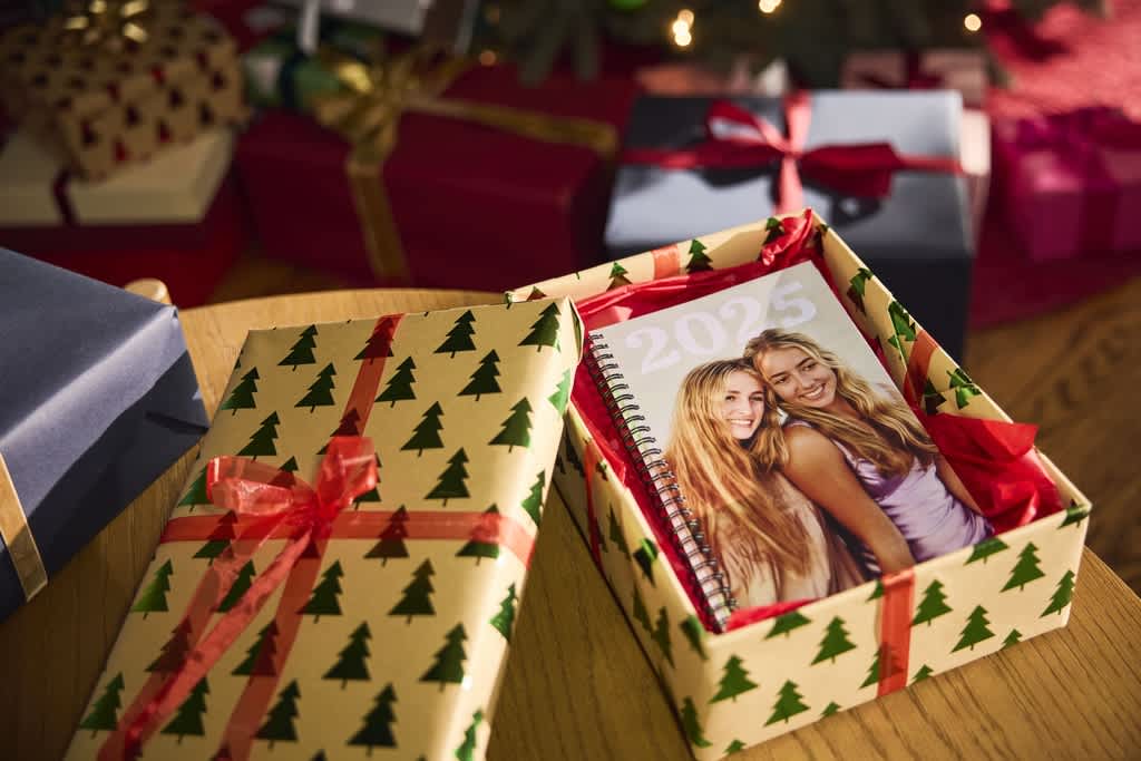 A personalized calendar sitting in a Christmas gift-wrapped box.