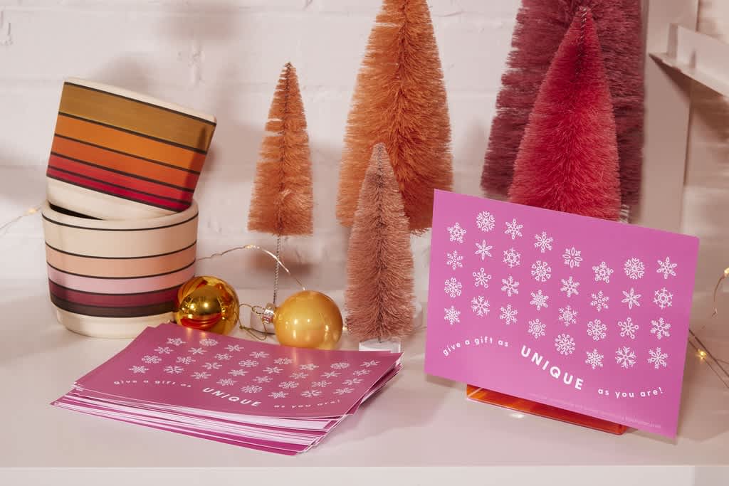 Pink glossy Christmas card with a white snowflake pattern and brand logo centered along the bottom.