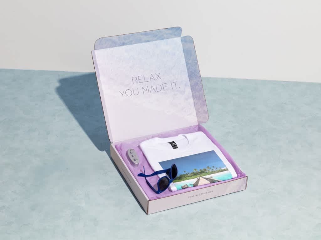 Promotional merch gift box with a custom T-shirt, branded sunglasses and printed packaging.