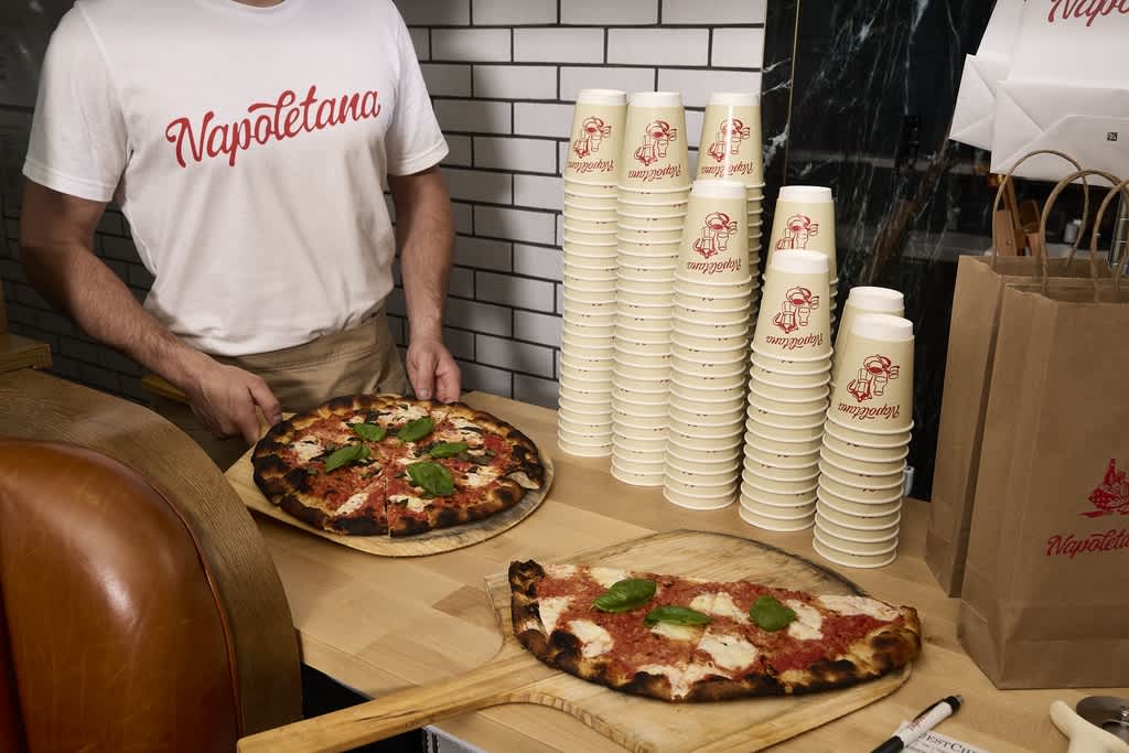 A pizza restaurant with stacks of branded paper cups.