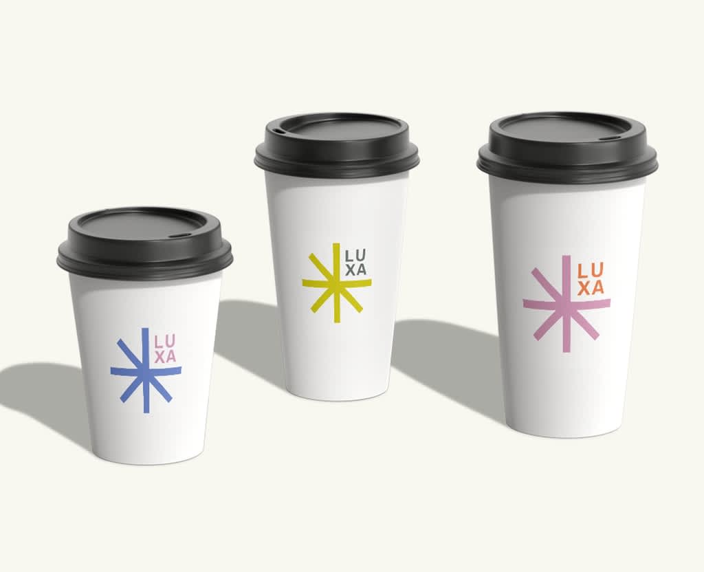 Three white paper cups with black lids and colorful branding.