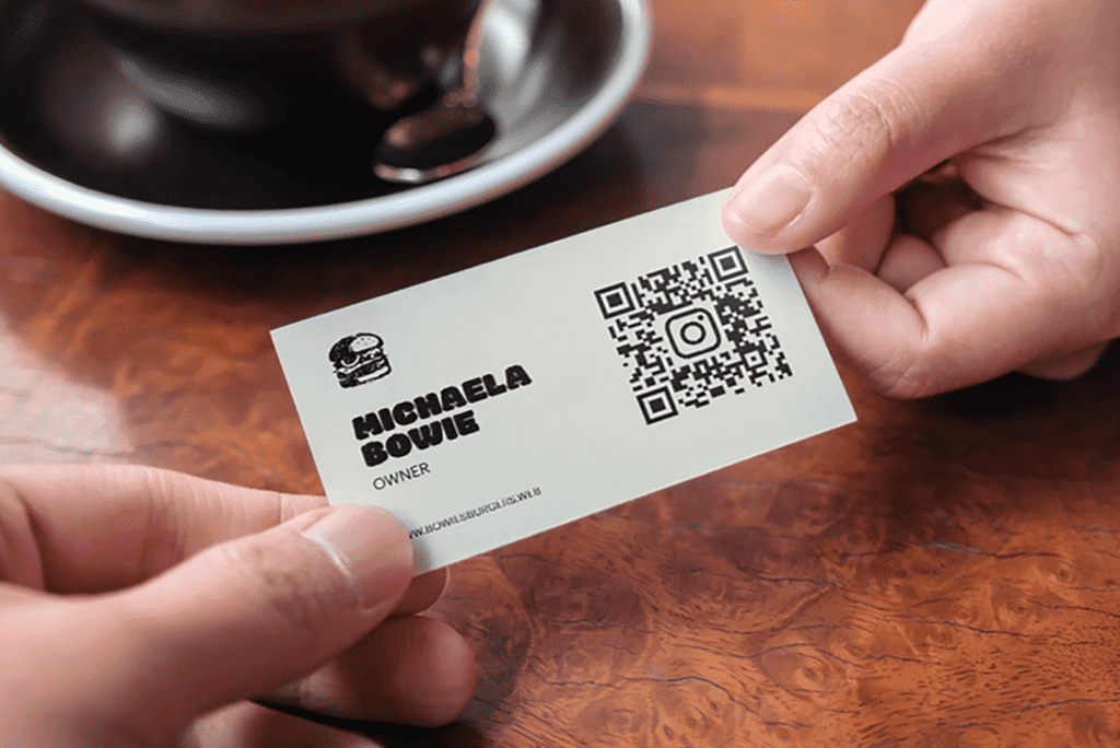 Business owner handing over their business card with an Instagram QR code.