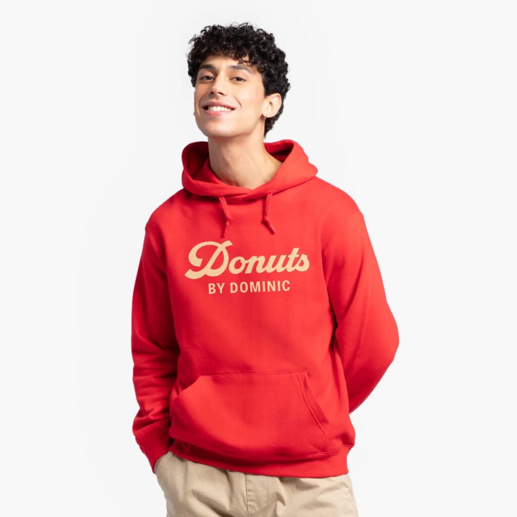 A person wearing a red branded hoodie with the Donuts by Dominic logo printed across the chest.