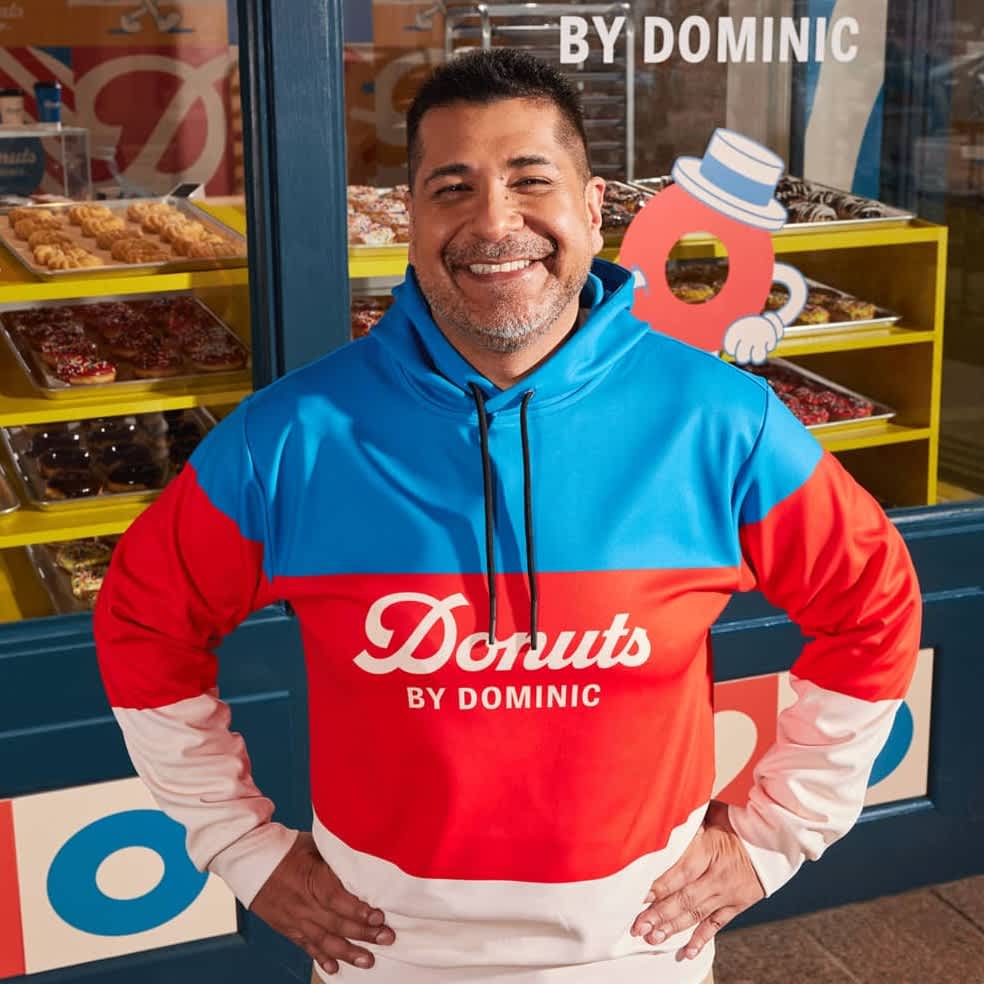 A small business employee wearing a multi-colored branded hoodie with a logo.