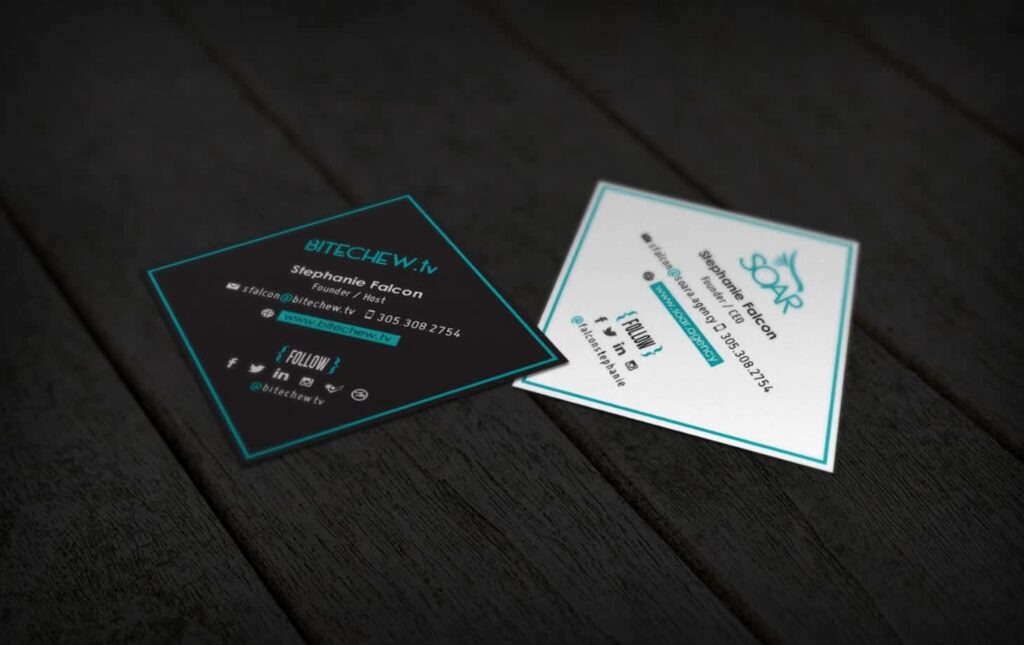 Two square business cards with teal accents and social media details on a dark wooden surface.