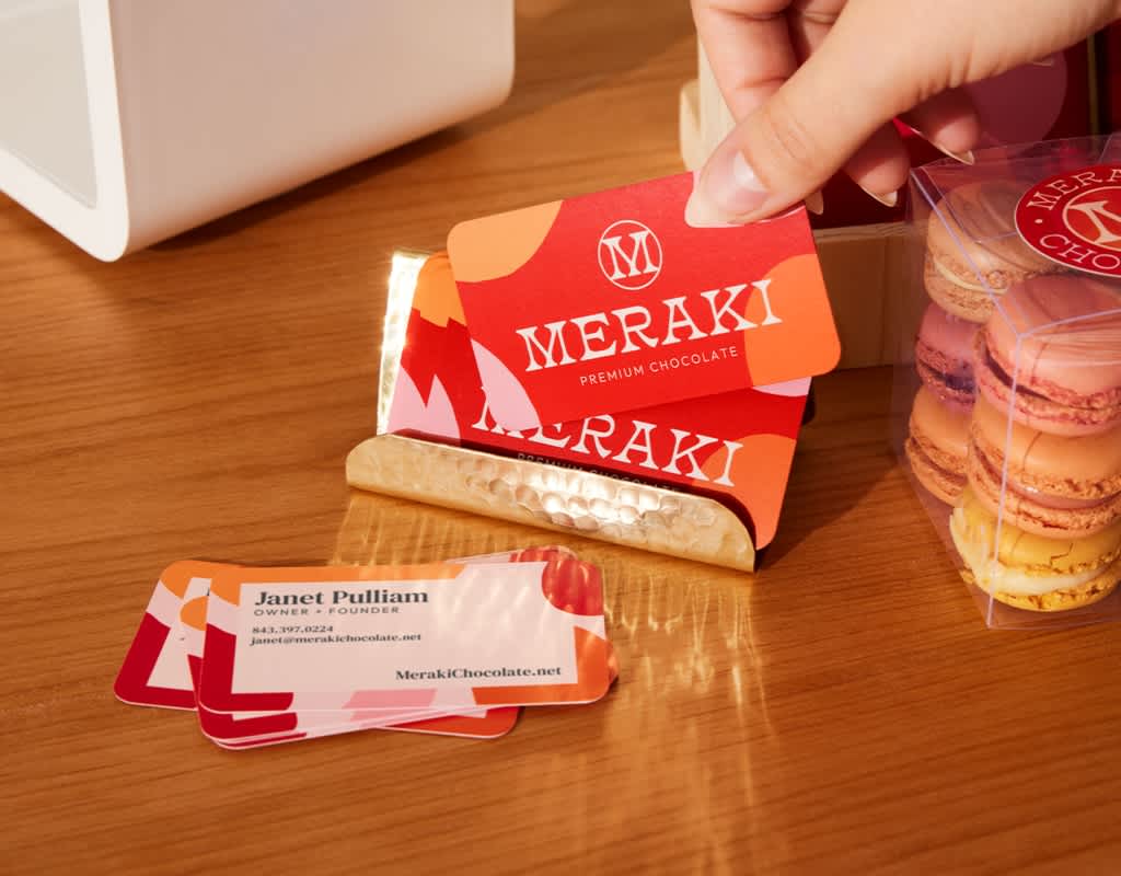 A stack of red and orange business cards with a clear white logo.