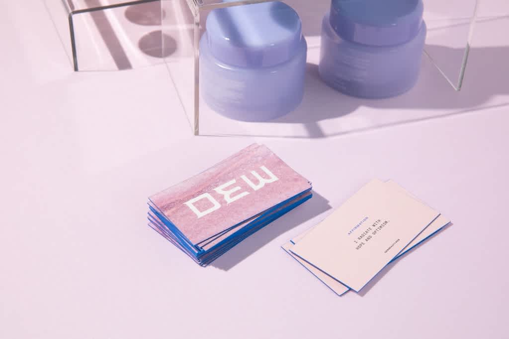 A stack of pink and blue business cards with a logo on one side and clear business information on the reverse.