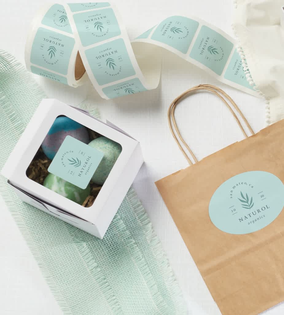 Small white packaging box with window panel, custom blue stickers and a paper bag.