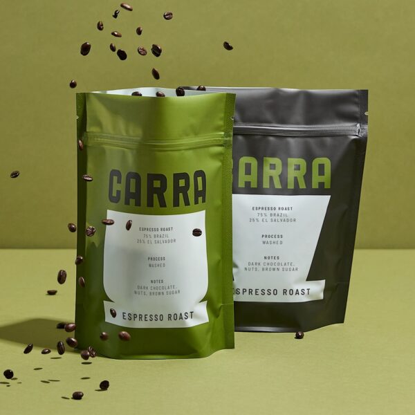 Two green and black CARRA espresso coffee pouches with resealable zippers, surrounded by scattered coffee beans.