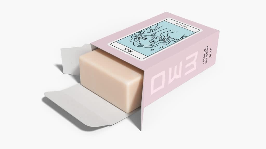 Small pink rectangular product package with light blue tarot card design and a bar of soap protruding from the top.