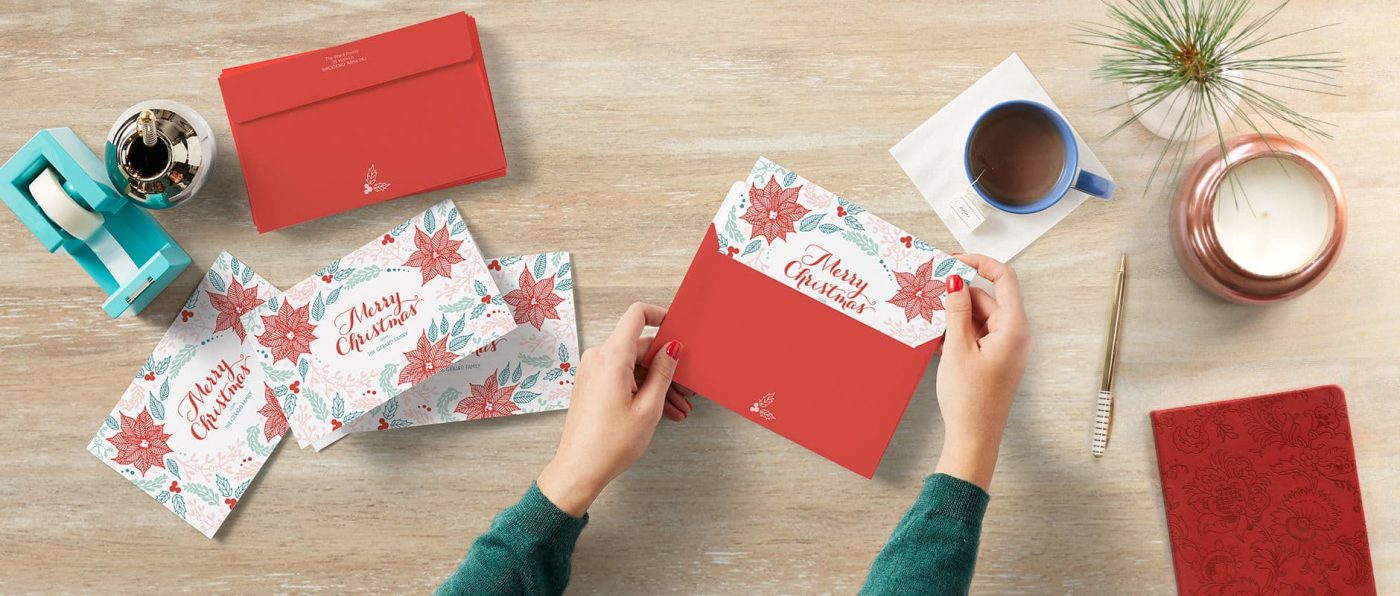Top view of signing and sealing Christmas cards at a desk with a coffee