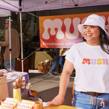 Outdoor event marketing booth at craft fair with branded apparel, signage and promotional display attracting visitors