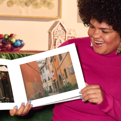 Smiling woman holding her custom photo book, proud of her creation.