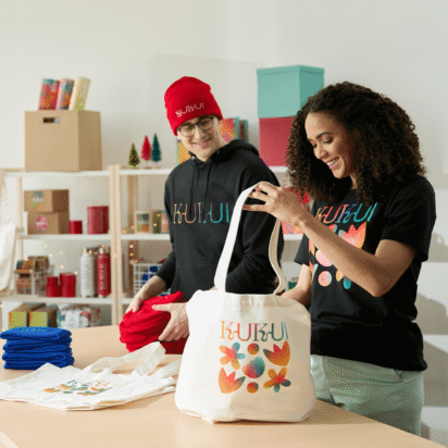 Two people preparing branded tote bags with colorful designs, showcasing creative swag bag ideas for events and businesses.