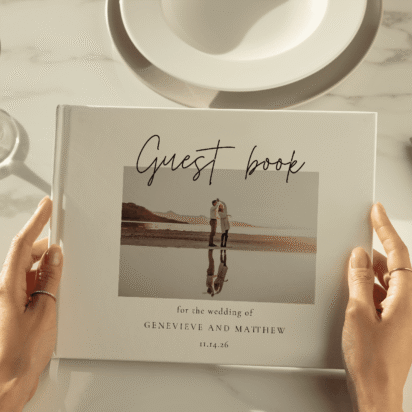 Close-up of a personalized wedding guest book held by a guest, featuring a photo of the couple and elegant script text.