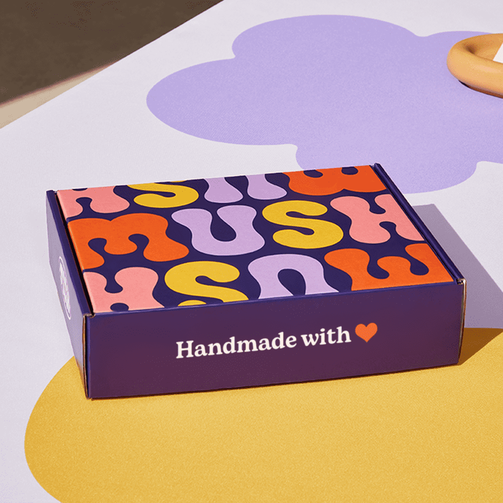 Closed purple custom mailer box with colorful design on exterior top panel and simple white text on front and side panels