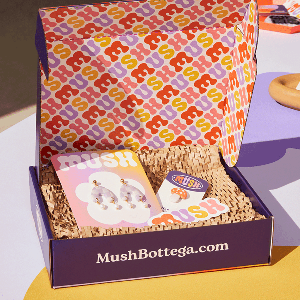 open custom mailer with website on front panel, colorful design on interior top panel and products resting on sustainable recycled paper padding inside