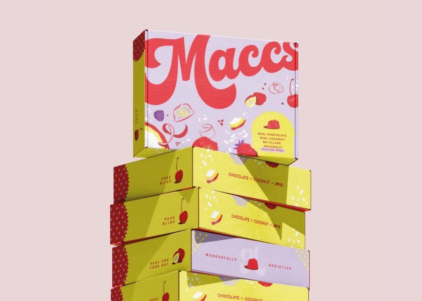 Colorful stacked product boxes with bold &ldquo;Maccs&rdquo; branding and fruit illustrations on a pastel background.