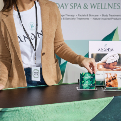 A person arranging brochures and promotional materials at a wellness brand trade show booth.